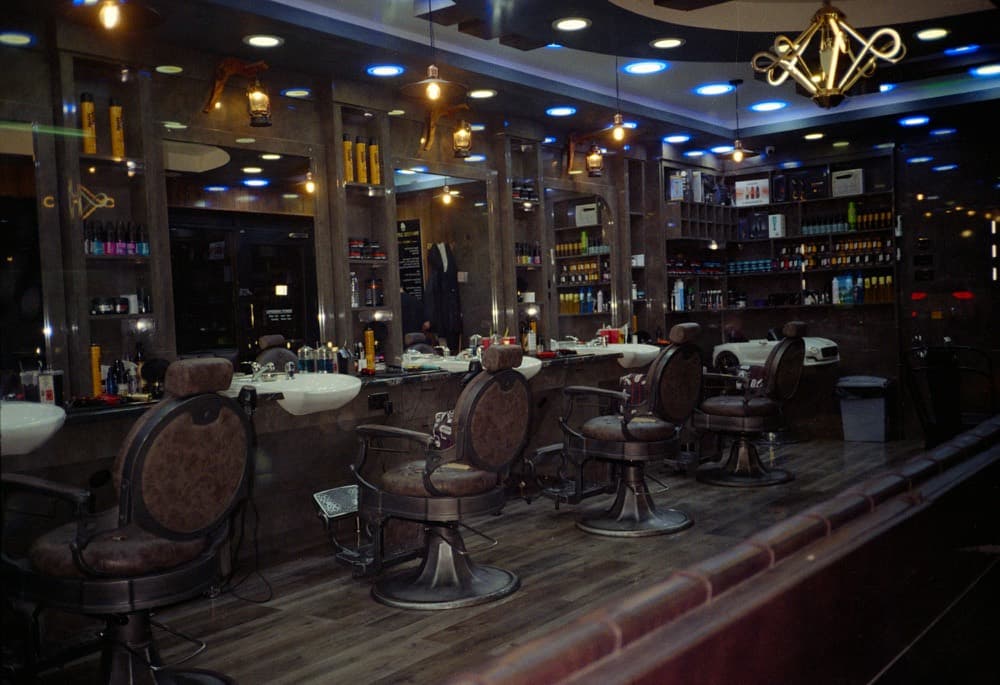 An empty barbershop at night, chairs facing lit mirrors